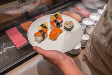 Close up photo of human holding dish of assorted sushiの写真素材