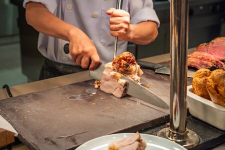 The restaurant chef cutting roasted pork meat at kitchenの写真素材
