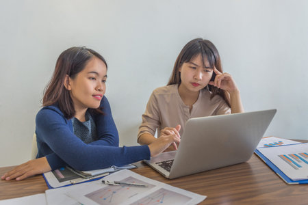 Two young ladies working on laptop and financial paperworks