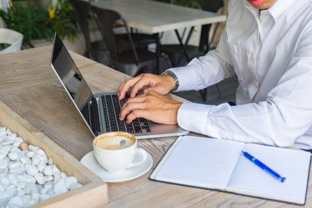 Businessman in white shirt using laptop at cafe