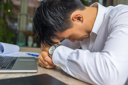 Tired businessman sitting with laptop and documents at office
