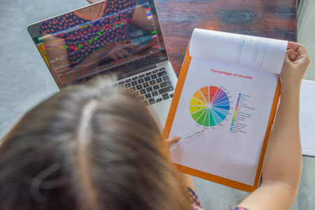 Financial executive working on laptop and pie chart document