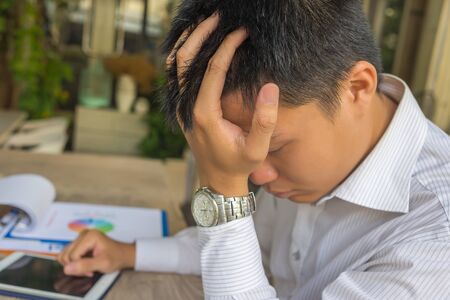 Frustrated young businessman having headache at business officeの写真素材