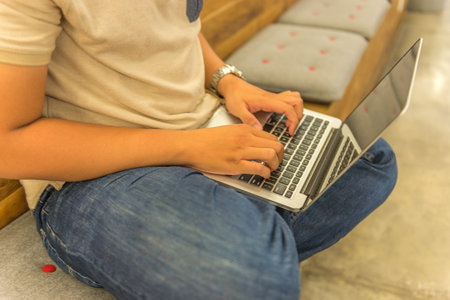Human comfortably sitting on bench and typing laptop keyboard