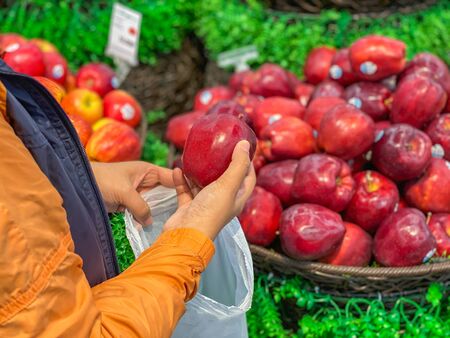 Woman buying and putting an apple into bio plastic bagの写真素材