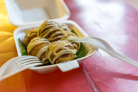 Tasty takoyaki topped with cream sauce in white plastic box