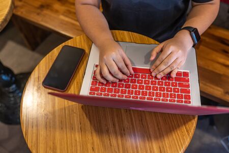 Human hand typing laptop keyboard next to smartphone on tableの写真素材