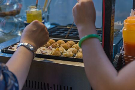Woman hands cooking Japanese Takoyaki- octopus balls on hot panの写真素材