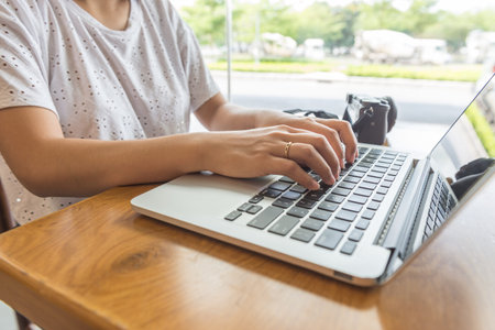 Female hands typing on laptop beside camera