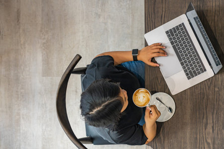 Freelancer using laptop and having cappuccino coffee on rustic table