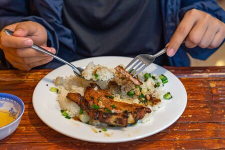 Closeup photo of woman eating delicious Vietnamese pork chop riceの写真素材