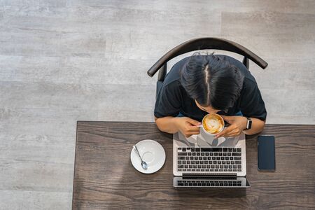 Overhead view photo of woman enjoying latte and using laptopの写真素材