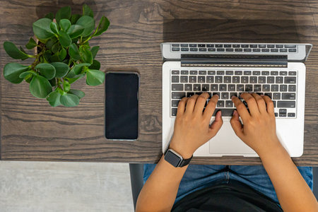 Overhead view photo of human hands typing laptop keyboard on rustic table