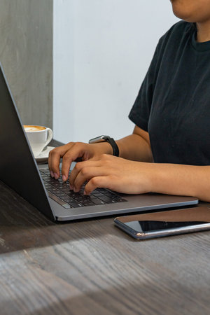 Closeup photo of female hands typing laptop next to smartphone