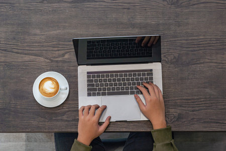 Top view of freelancer hand working on laptop at coffee shop