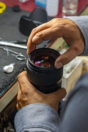 Closeup photo of technician with amputated finger cleaning camera lens