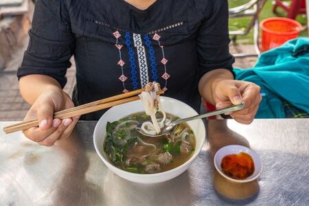 Young woman tourist Pho noodle soup - famous local food of Vietnamの写真素材