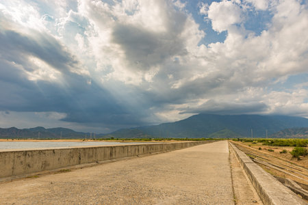 Empty embankment or causeway under overcast sky with little sunbeam