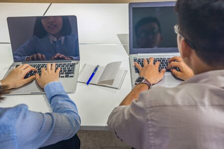 Rear view of woman and man using laptop at business workplaceの写真素材