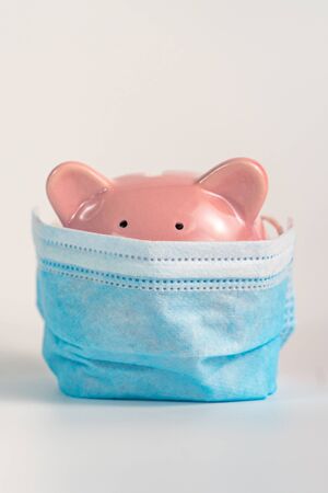 Vertical photo of piggybank wearing medical mask on white backgroundの写真素材