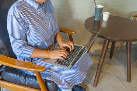 Businesswomans hands typing laptop keyboard at coffee table