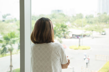Woman looking out from her office windowの写真素材