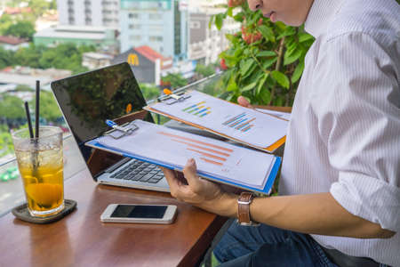 Side view of young man reading finance document at the balconyの写真素材