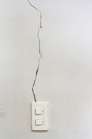 White wall with severe cracked groove near the light switchの写真素材