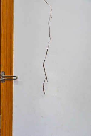 Vertical photo of cracked wall texture next to the doorの写真素材