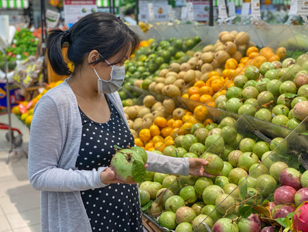 Asian woman buying tropical fruit at groceries storeの写真素材