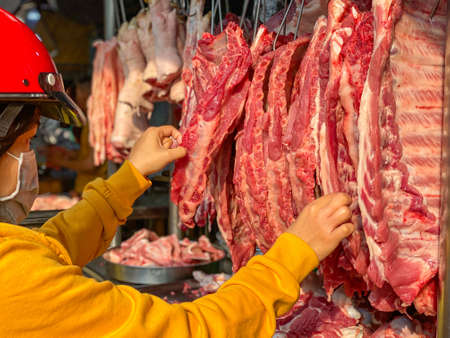 Vietnamese woman buying pork spare ribs at meat marketの写真素材