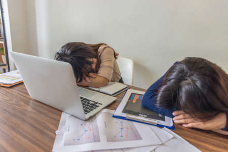 Tired and frustrated freelancer sleeping on the working tableの写真素材