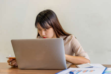 Asian office woman working on laptop and documentsの写真素材