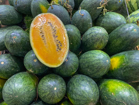 Pile of oval shaped yellow watermelon at fruit marketの写真素材
