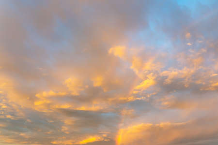Golden clouds and rainbow on dramatic sky at sunsetの写真素材