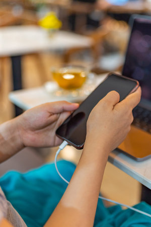 Vertical photo of female using smartphone while charging battery