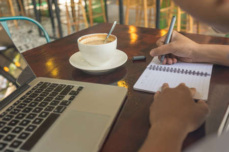 Male hand writing notes in the coffee shopの写真素材