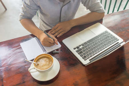 Young man writing into notesの写真素材