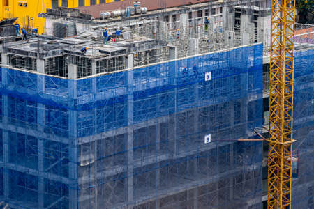 Worker working on new construction site with crane and mechanical equipmentsの写真素材