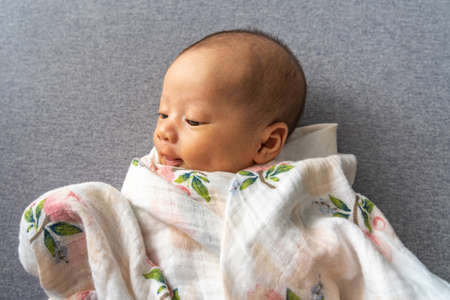 New born infant with dimple cheek lying on grey backgroundの写真素材