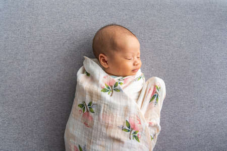 New born Asian infant sleeping on grey backgroundの写真素材