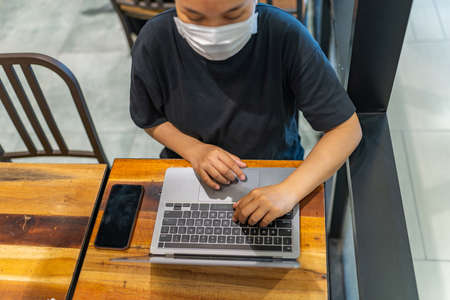 High angle view photo of woman wearing protective mask and using laptopの写真素材
