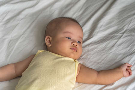 Cute 4 months old Asian baby on lying on the bedの写真素材