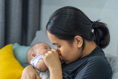 Asian mother kissing her babys hand while she sleepingの写真素材