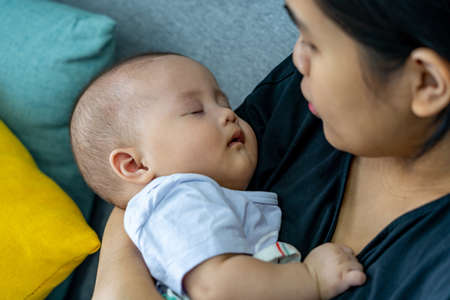 Lovely baby sleeping on her mothers handの写真素材