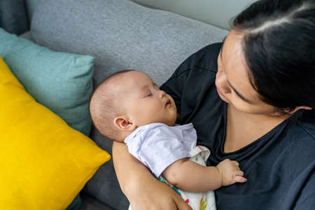 Adorable baby girl sleeping on her mothers handの写真素材