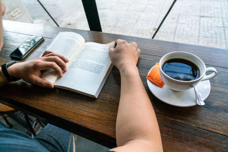 Man reading books and drinking coffee in the morningの写真素材