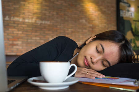 Portrait of a tired young businesswoman sleeping the cafeの写真素材