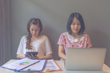 Two young female freelancer using laptop and tablet while workingの写真素材