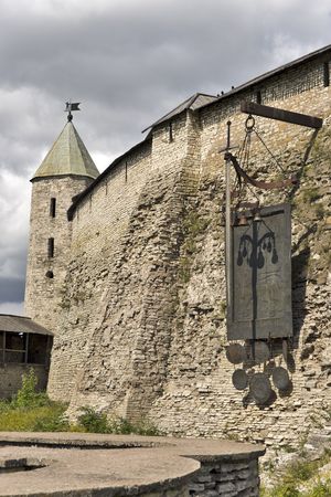 Harsh wall of ancient Pskov kremlin in Russia with monument of shield and swordの写真素材